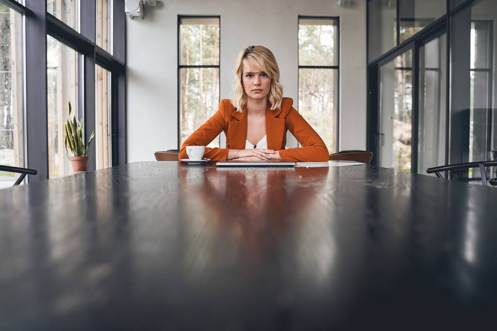 Ernsthafte blonde Dame sitzt in ihrem Büro - Foto, Bild