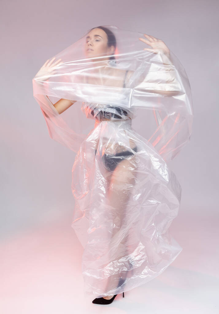 Tyttö poseeraa muovikalvosta tehdyssä mekossa. Covid19 muoti muotokuva
. - Valokuva, kuva