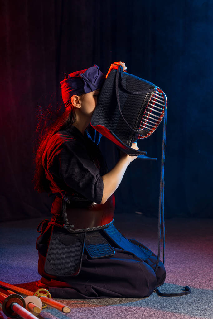 Genç kadın Kendo dövüşçüsü başına maske takıyor. - Fotoğraf, Görsel