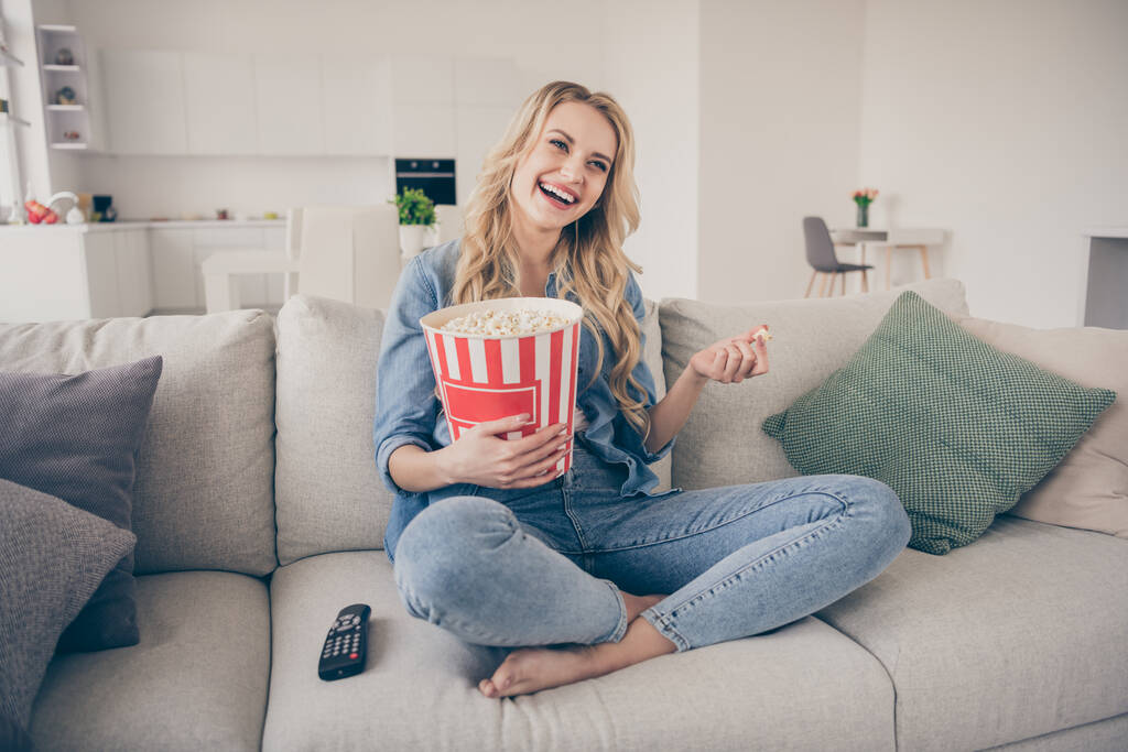 Photo of beautiful barefoot lady relaxing sitting comfy couch eat popcorn legs crossed watch comedy romantic movie positive emotions stay home quarantine time living room indoors - Photo, Image