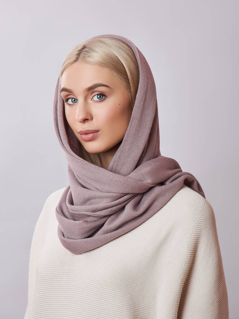 Mulher muçulmana europeia com um cabelo loiro em um xale de lenço de cabeça vestido em sua cabeça. Menina bonita em suéter com pele macia, cosméticos naturais
 - Foto, Imagem