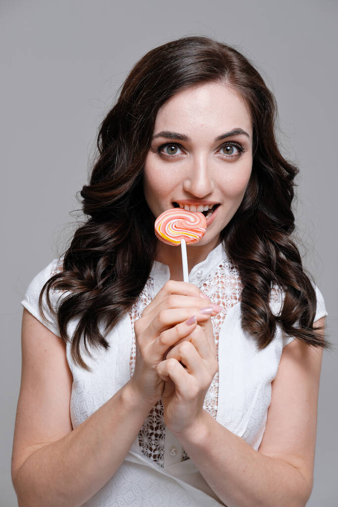 Studio portrait of woman holding colorful lollipop - Photo, Image