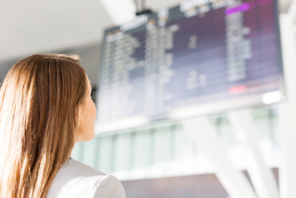 空港のフライトディスプレイ画面を見ているビジネスマン女性 - 写真・画像