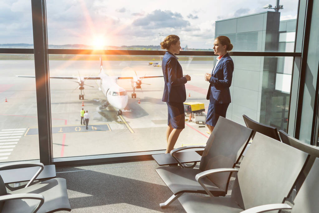 Молоді привабливі співробітники аеропорту стоять під час розмови під час перерви в аеропорту
 - Фото, зображення