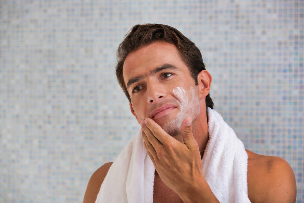 Portret atrakcyjnego mężczyzny myjącego twarz pianką do twarzy w łazience - Zdjęcie, obraz