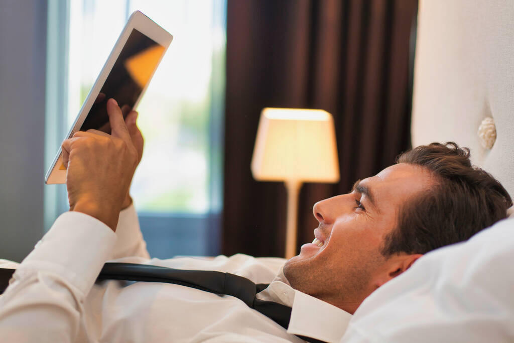 Érett üzletember fekszik az ágyon, miközben a digitális tabletta otthon - Fotó, kép