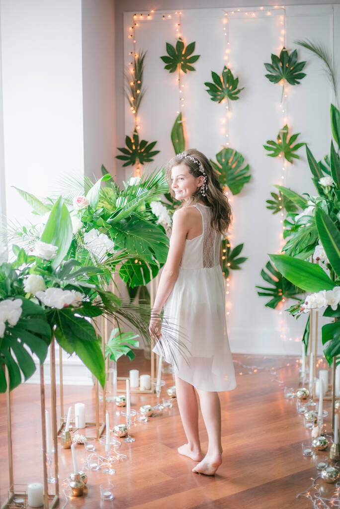 Houkutteleva nuori tyttö romanttinen valkoinen mekko keskuudessa trooppinen vehreys ja valkoinen orkideat, ruusut ja liljat. Kauneus ja muoti
 - Valokuva, kuva