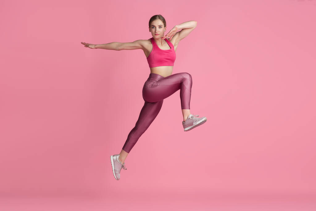 Красивая молодая спортсменка, практикующая на розовом фоне студии, монохромный портрет
 - Фото, изображение
