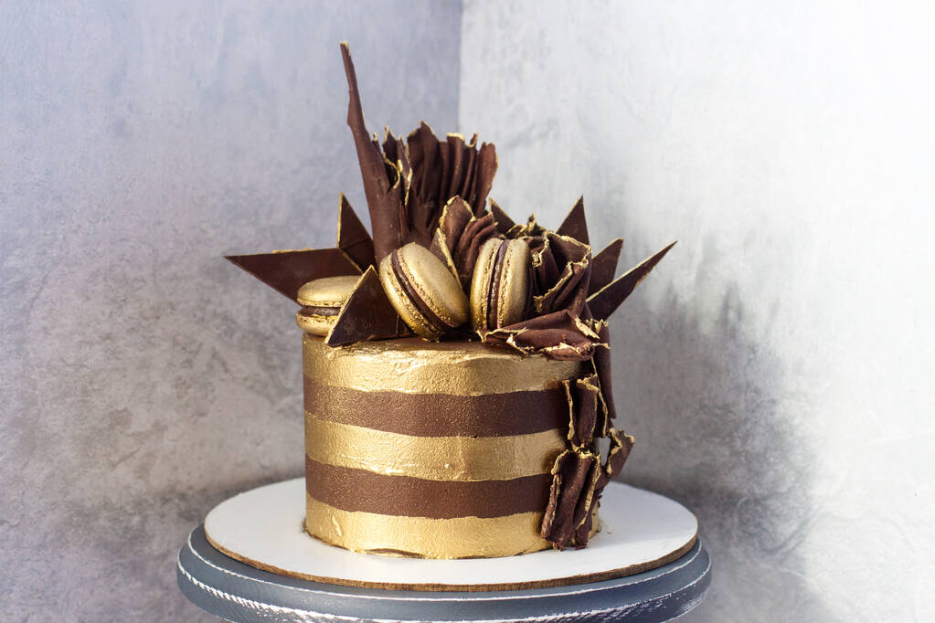 Altın çizgili çikolatalı doğum günü pastası, koyu çikolata süslemesi ve badem kurabiyesi. Gri arkaplan. - Fotoğraf, Görsel