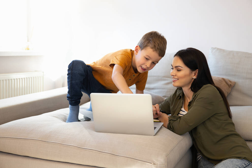 Fröhliche Frau hilft Sohn beim Online-Lernen von zu Hause aus - Foto, Bild