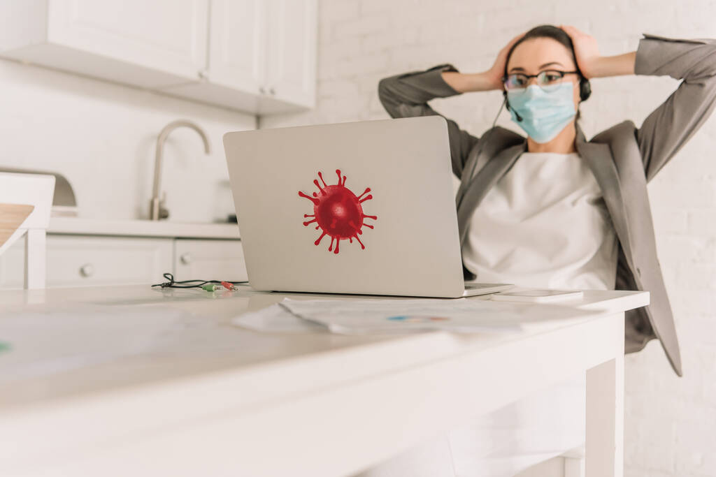 вибірковий фокус втомленої бізнес-леді в медичній масці і гарнітурі торкаючись голови, дивлячись на ноутбук з бактеріями наклейка на кухні
 - Фото, зображення