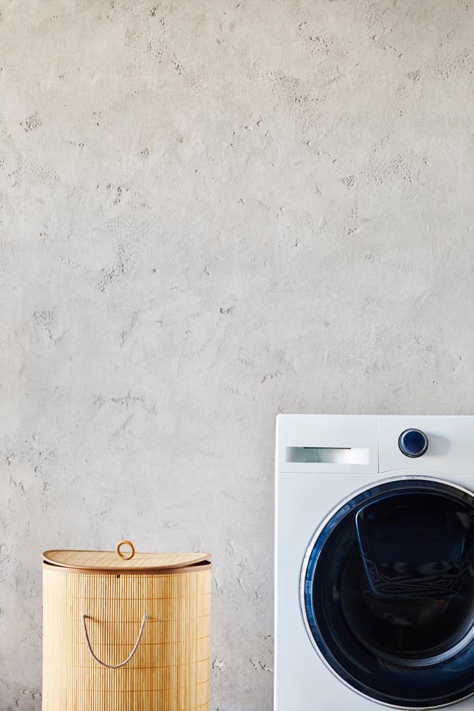 cesta de roupa perto de máquina de lavar roupa branca no banheiro moderno
  - Foto, Imagem