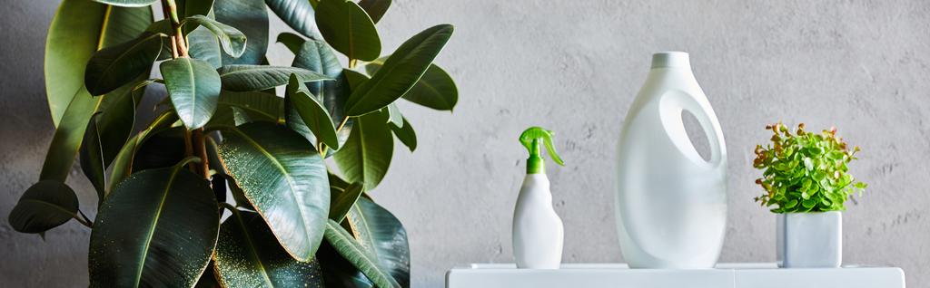 Modern banyoda yeşil bitkilerin yanında panoramik deterjan ve sprey şişeleri.  - Fotoğraf, Görsel