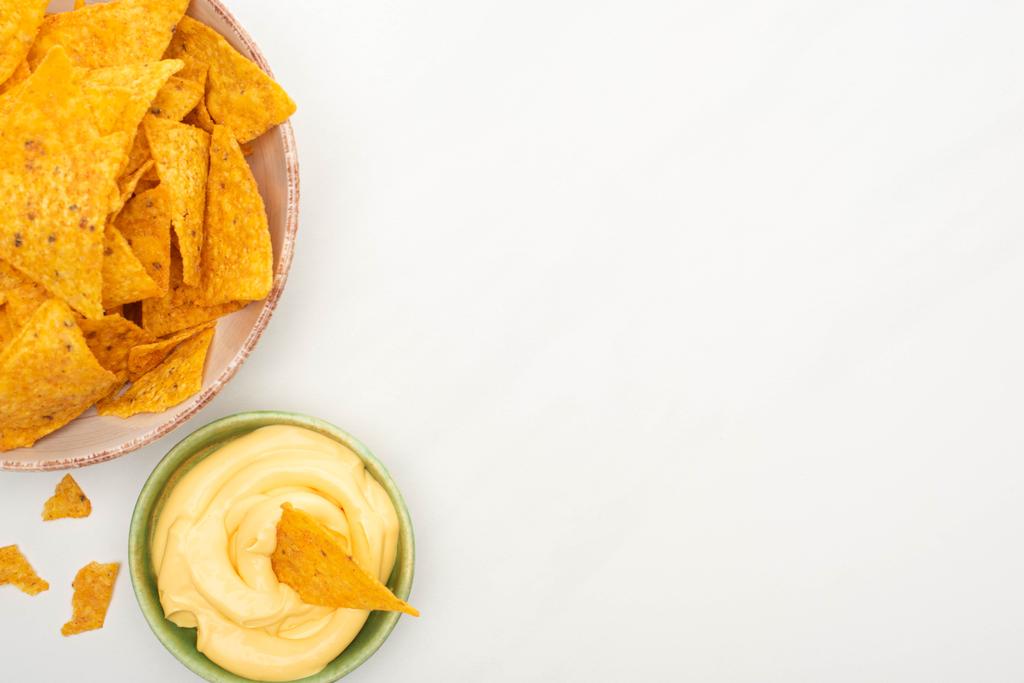 vista superior de nachos de maíz con salsa de queso sobre fondo blanco
 - Foto, Imagen