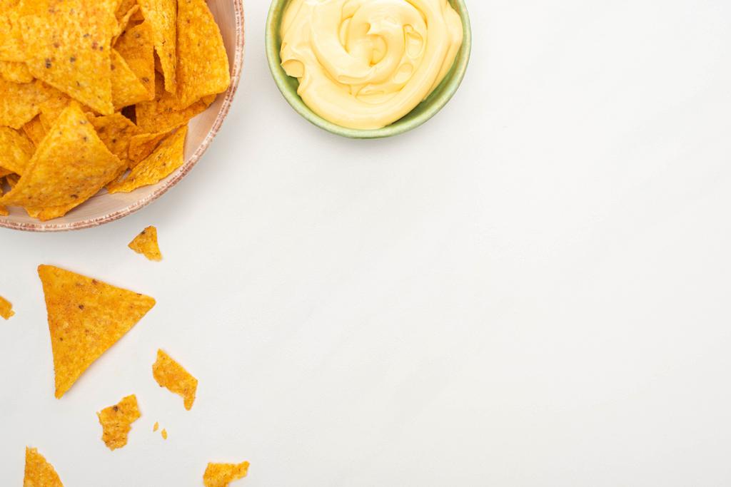 vrchní pohled na kukuřičné nachos se sýrovou omáčkou na bílém pozadí - Fotografie, Obrázek