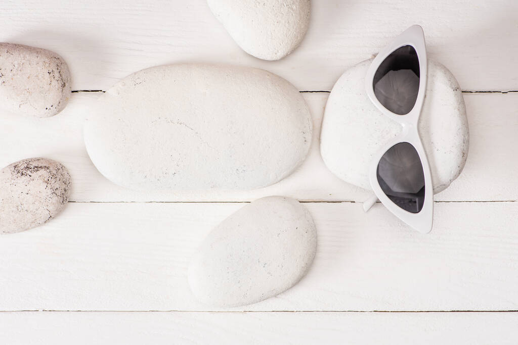 Vista superior de piedras de mar con gafas de sol sobre superficie de madera blanca
 - Foto, imagen