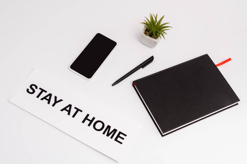 смартфон с чистым экраном рядом с ручкой, ноутбуком, растением и бумагой с домашней надписью на белом
  - Фото, изображение
