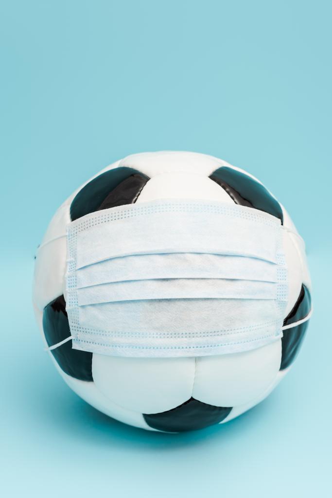 fotbalový míč v lékařské masce na modré  - Fotografie, Obrázek
