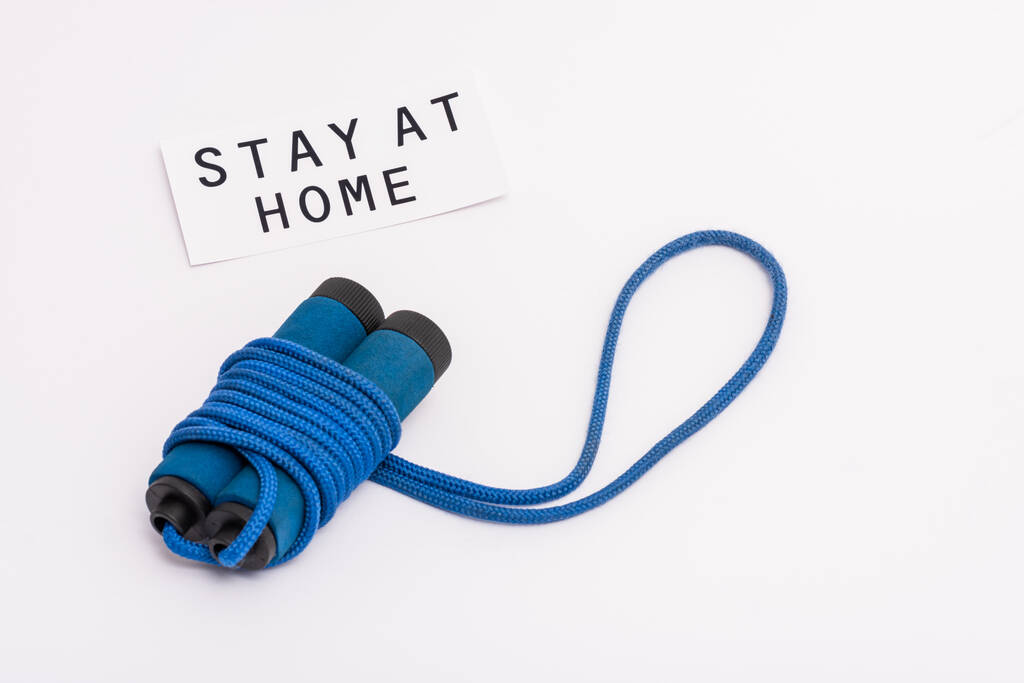 blue skipping rope near paper with stay at home lettering on white with copy space - Photo, Image
