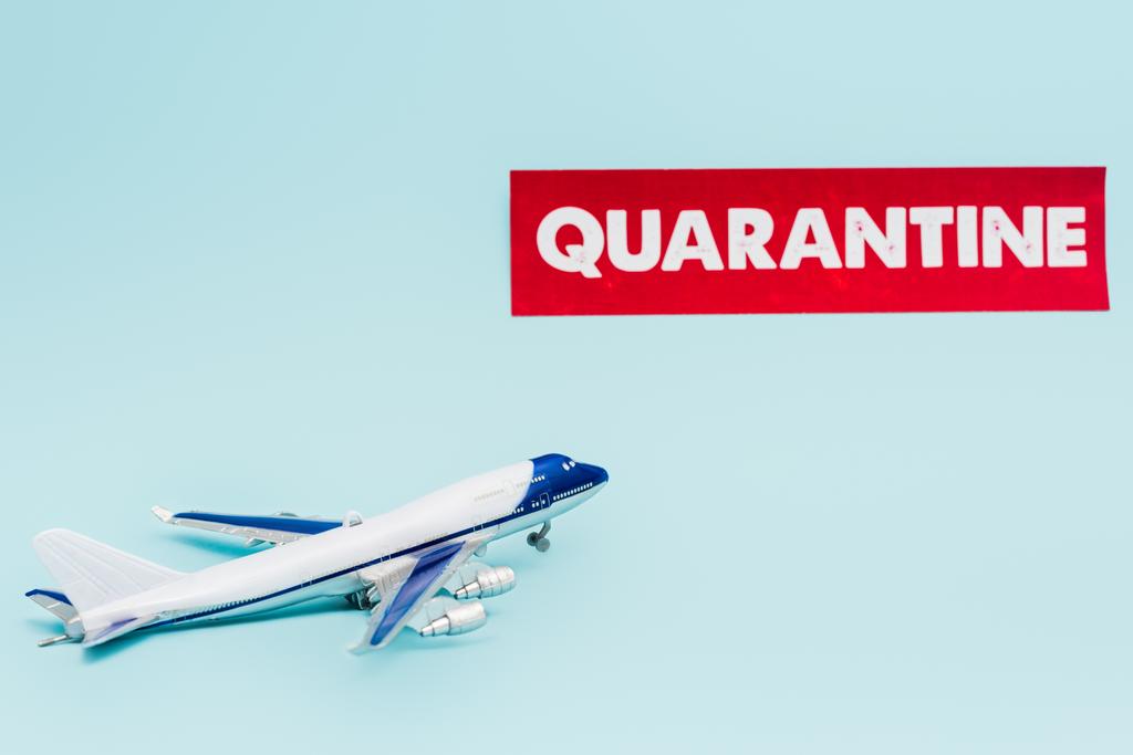 Spielzeugflugzeug in Papiernähe mit Quarantäne-Schriftzug isoliert auf blau  - Foto, Bild