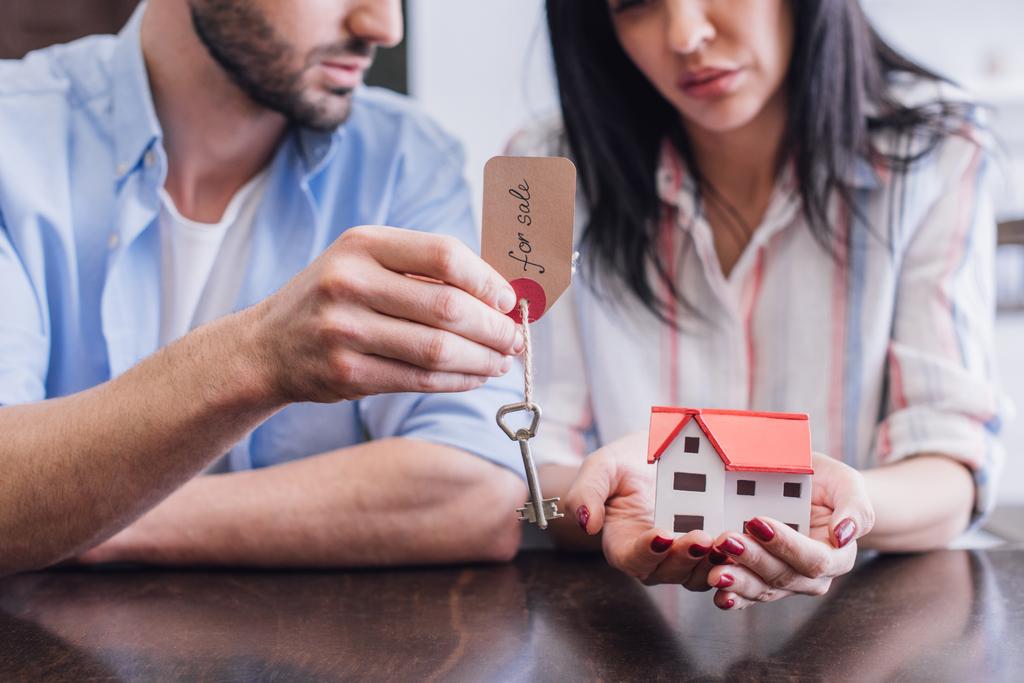 Oříznutý pohled na bankroty ukazující klíč s na prodej nápisy a dům model u stolu na pokoji - Fotografie, Obrázek