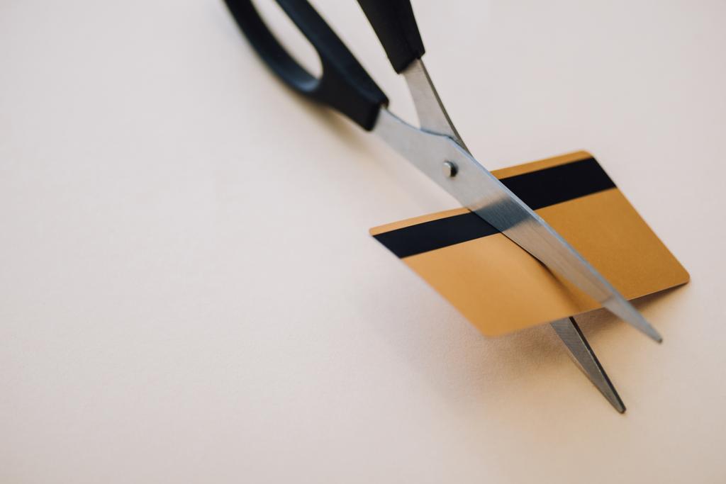 Vista de ángulo alto de la tarjeta de crédito con tijeras en blanco
 - Foto, Imagen