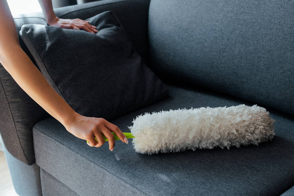 vista recortada de la chica limpiando el polvo del sofá con el plumero
 - Foto, imagen