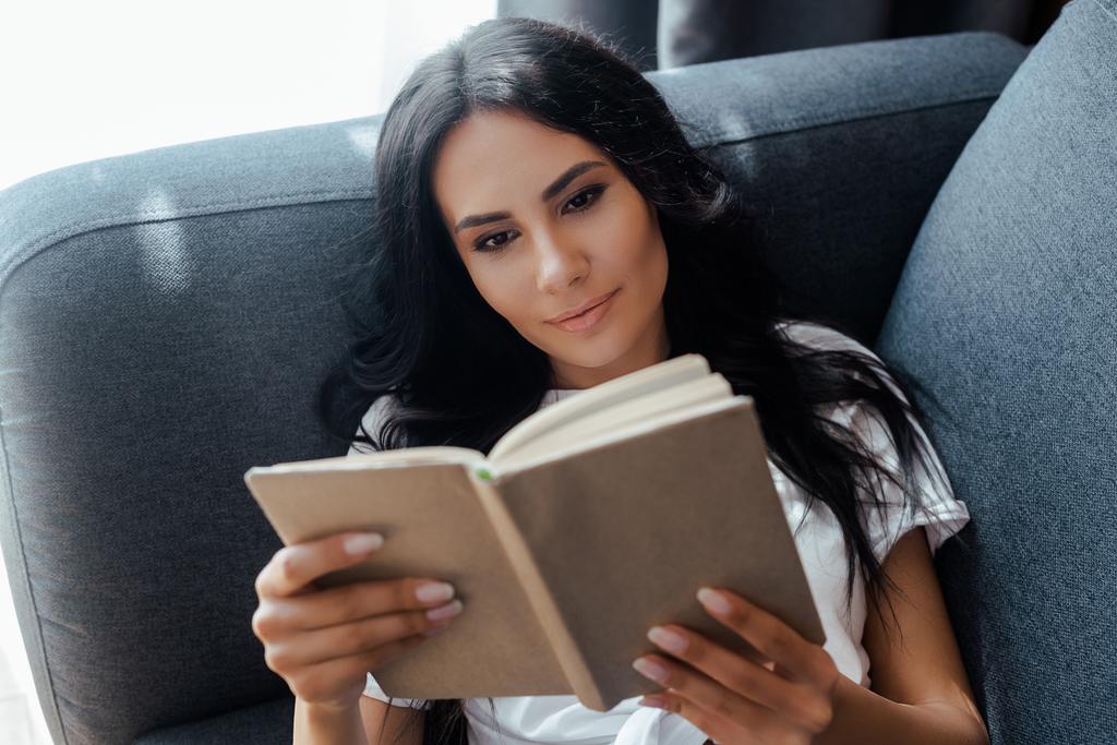 mulher feliz ler livro no sofá em casa
 - Foto, Imagem