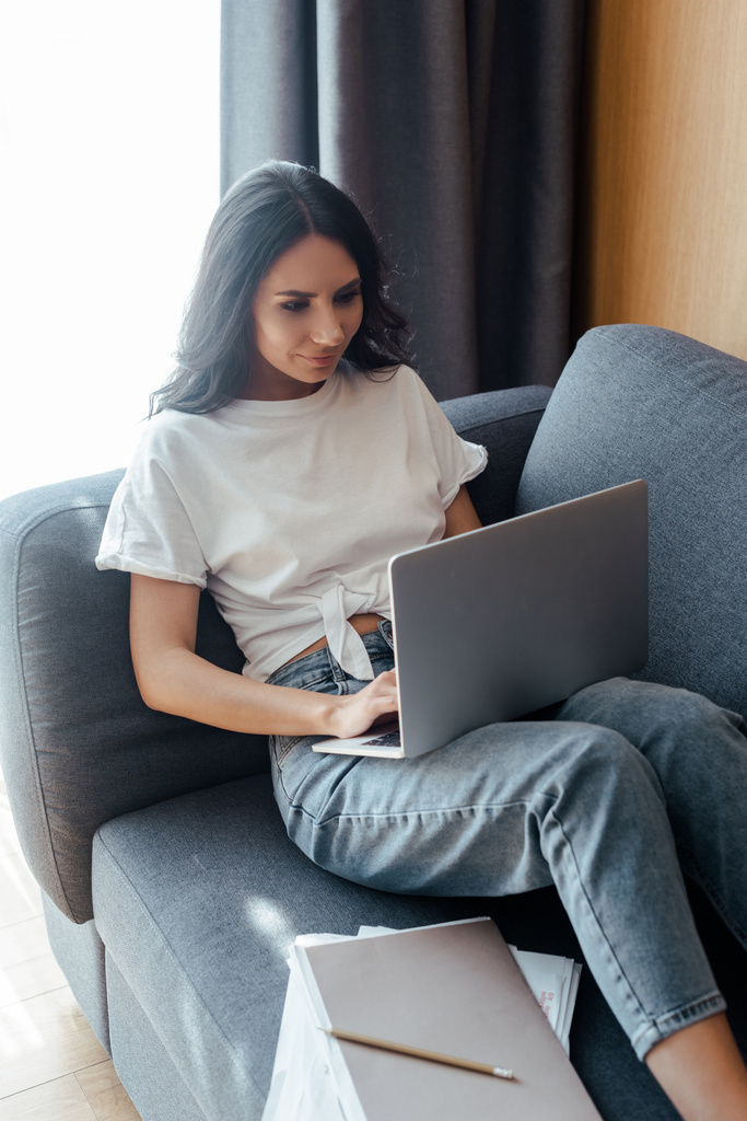 belle femme travaillant sur ordinateur portable avec des documents d'affaires sur canapé
 - Photo, image