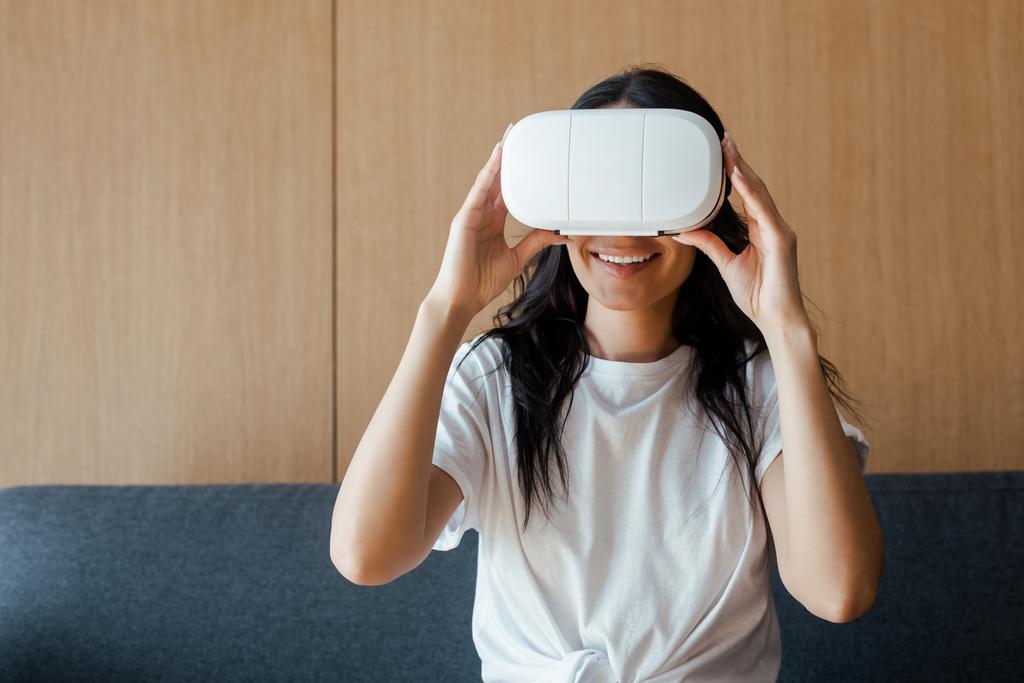 smiling young woman using virtual reality headset at home - Photo, Image