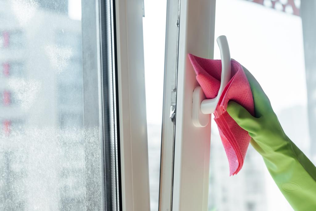 vista recortada de la mujer en guante de goma manija de la ventana de limpieza con trapo rosa
  - Foto, Imagen