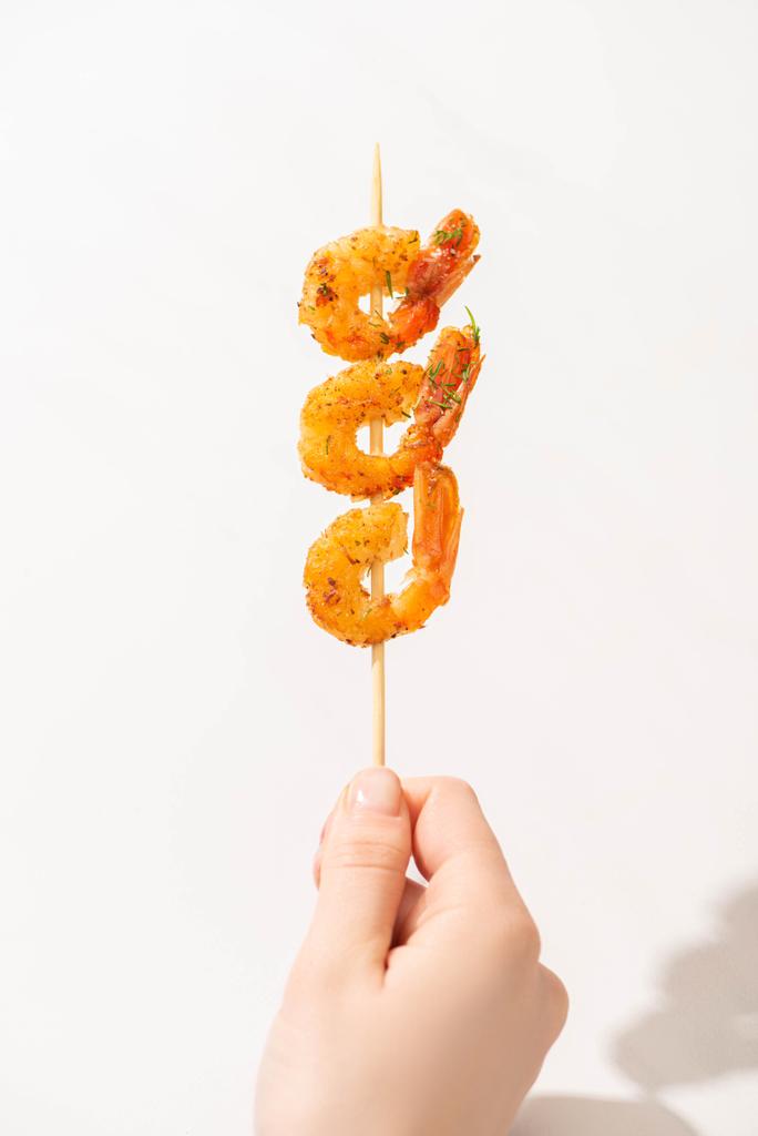 vista cortada de mulher segurando saborosos camarões fritos no espeto no fundo branco
 - Foto, Imagem