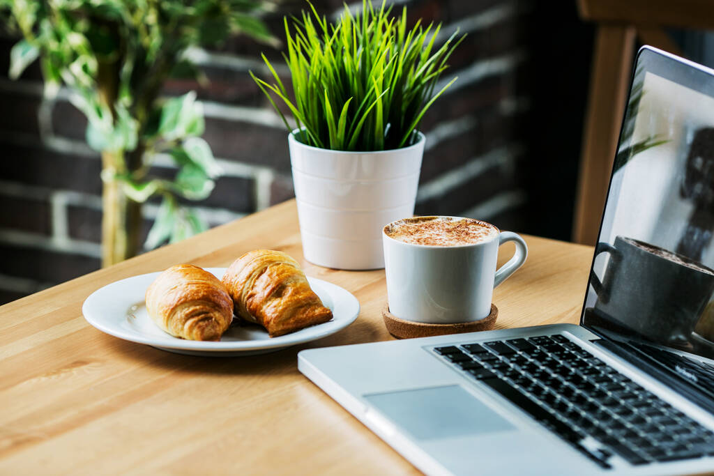 technologie, business en modern woonconcept - open voor het sluiten van de laptop en koffiebeker op tafel in café  - Foto, afbeelding