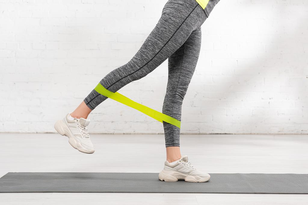 ostříhaný pohled na ženu cvičící s páskou odporu na fitness podložce - Fotografie, Obrázek