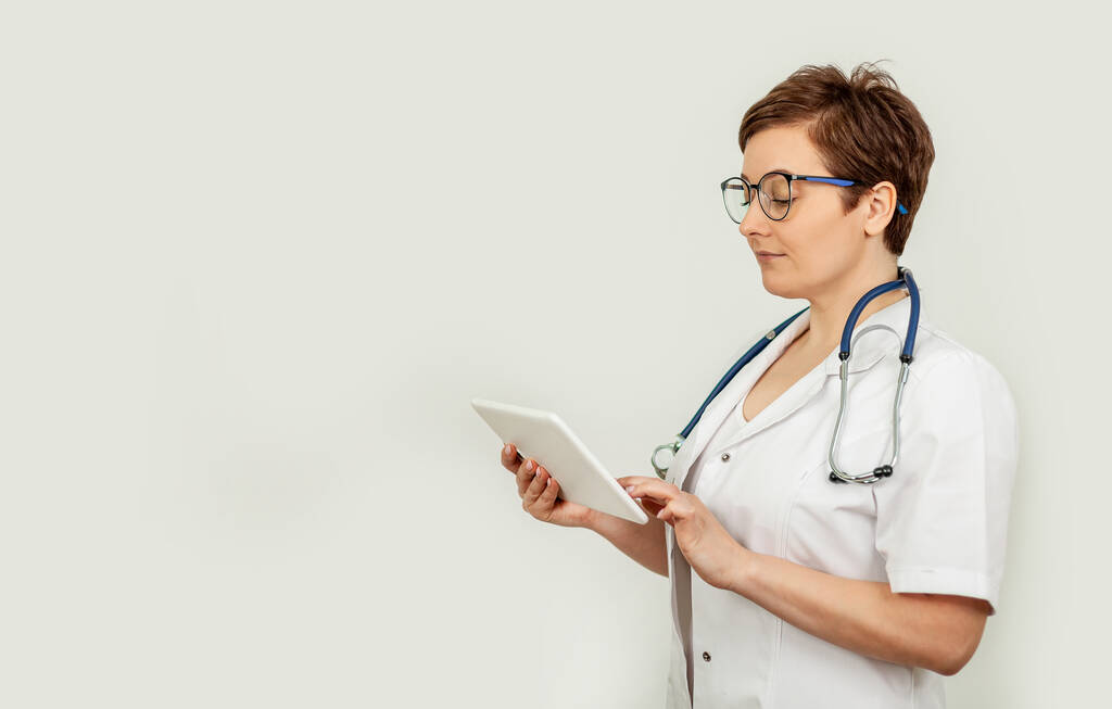Портрет женщины-врача, использующей свой цифровой планшет. Женщина-врач с помощью таблеток и проверки с анализом
 - Фото, изображение
