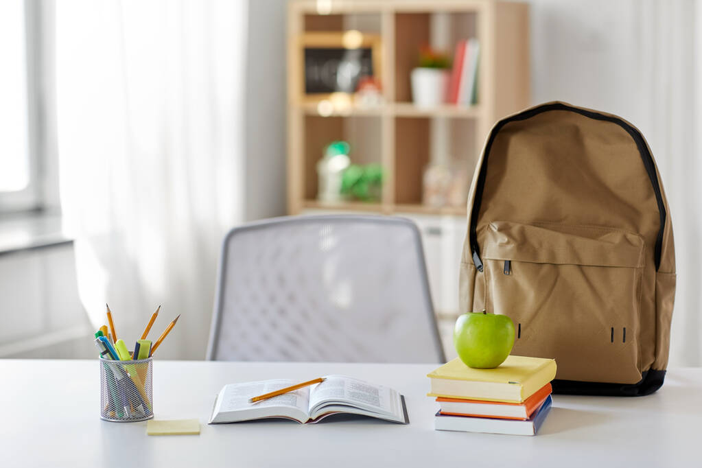 boeken, appel en schoolbenodigdheden op tafel thuis - Foto, afbeelding