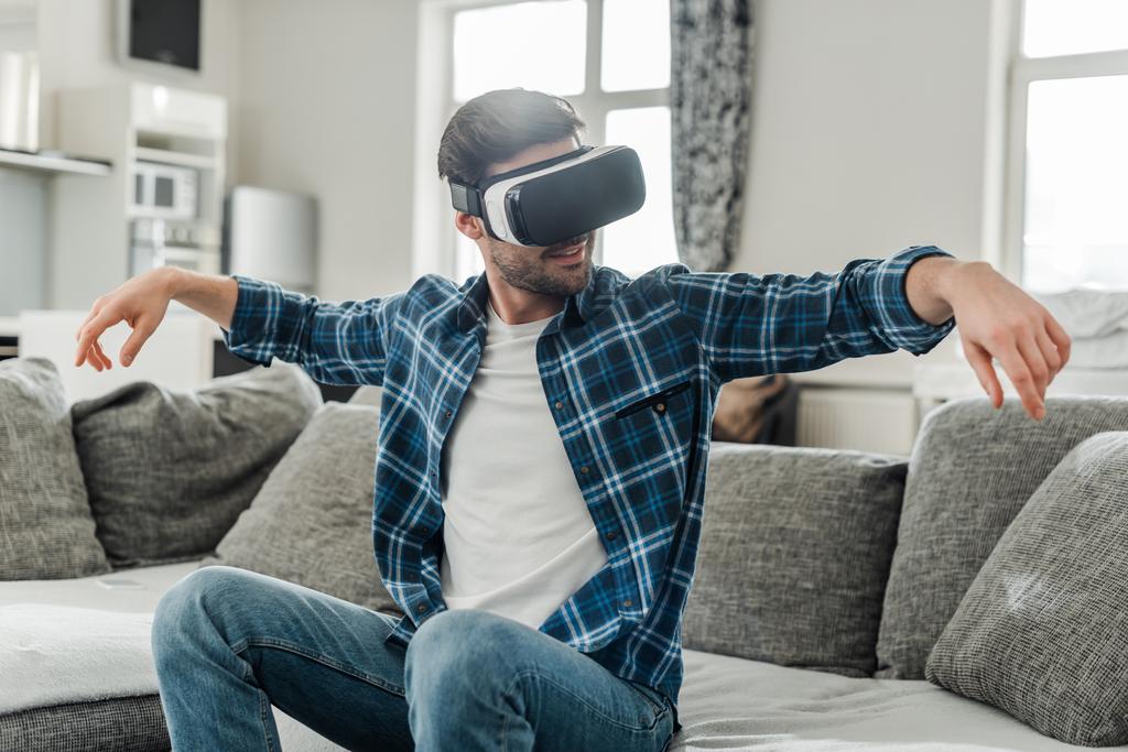 Mosolygós férfi használ virtuális valóság headset kanapén  - Fotó, kép