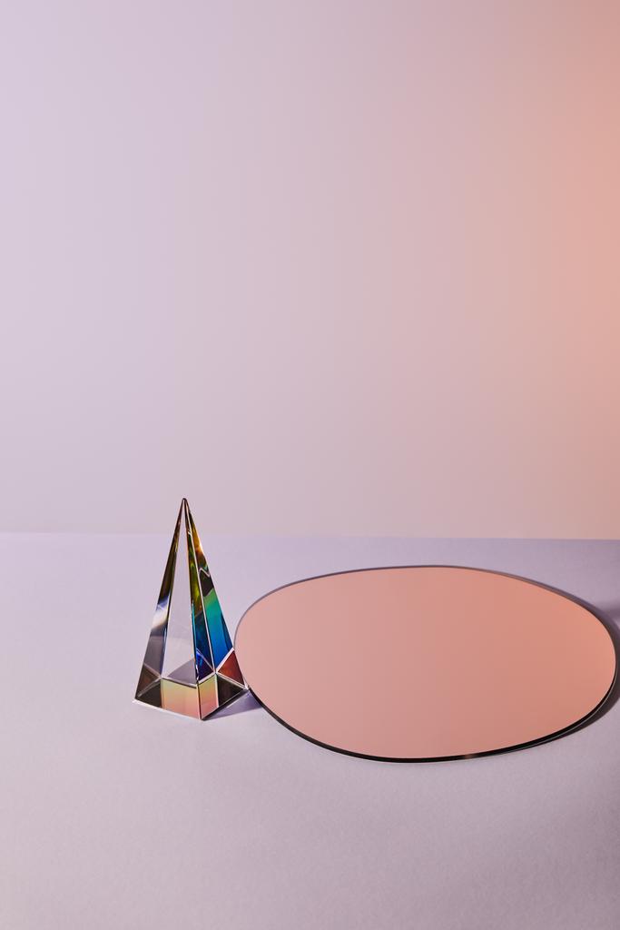 Kristall transparente Pyramide und runder Spiegel auf violettem Hintergrund - Foto, Bild