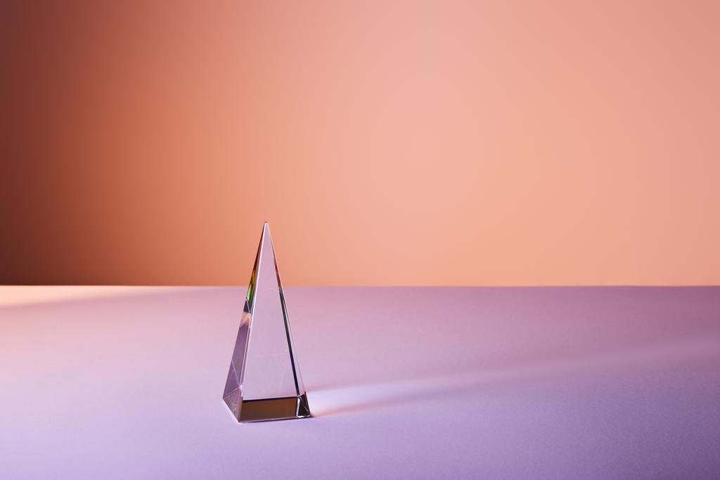 прозрачная пирамида с отражением света на фиолетовом и оранжевом фоне
 - Фото, изображение