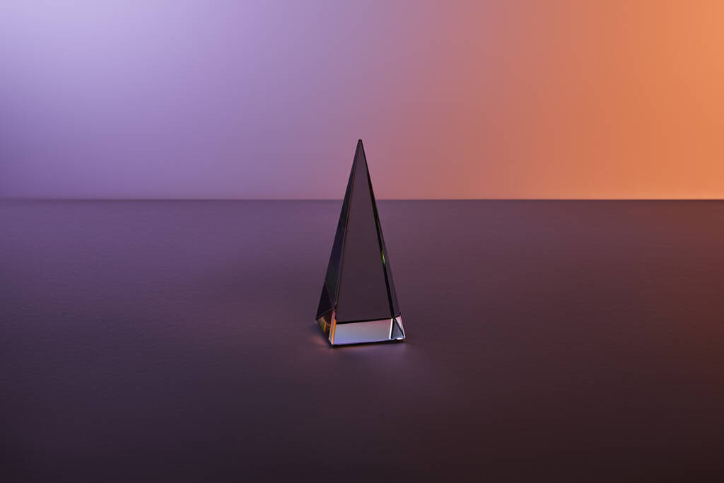 pirámide transparente de cristal con reflejo de luz sobre fondo púrpura oscuro
 - Foto, Imagen