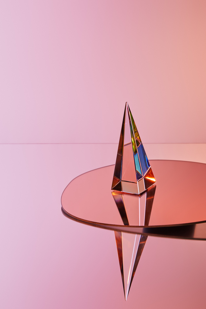 Kristall transparente Pyramide mit Reflexion auf rundem Spiegel auf rosa Hintergrund - Foto, Bild