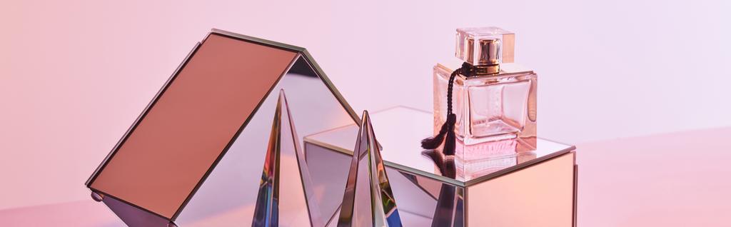 Parfüm şişesinin yanında kristal şeffaf piramit ve pembe arka planda ayna küpleri, panoramik mahsul - Fotoğraf, Görsel