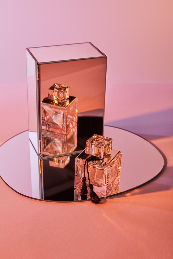 μπουκάλι άρωμα σε στρογγυλό καθρέφτη με κύβο σε ροζ φόντο - Φωτογραφία, εικόνα