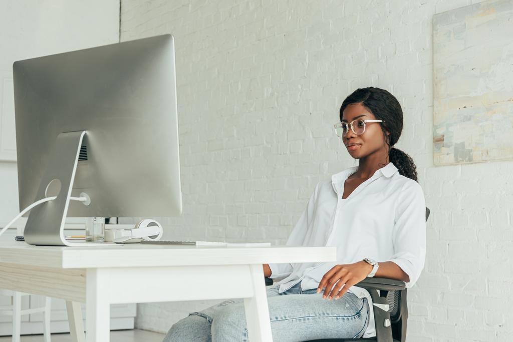 joven, atractivo afroamericano freelancer mirando el monitor de la computadora mientras trabaja en casa
 - Foto, Imagen