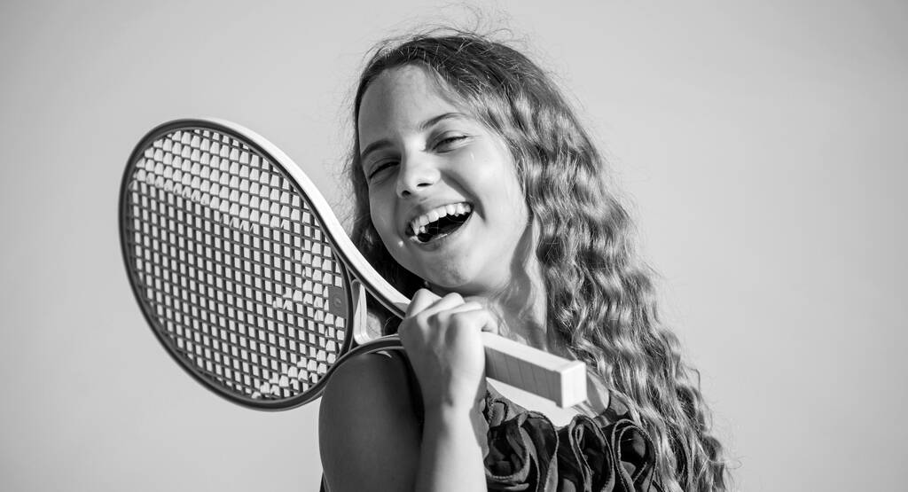 Καλοκαιρινή διασκέδαση Αθλητικός αγώνας. Παιχνιδιάρικο χαρούμενο παιδί. Ευτυχισμένη παιδική ηλικία. Απόλυτα. Συναισθηματικό μωρό. Ενεργή ζωή. Παιδί παίζει τένις μπλε φόντο ουρανό. Σπορ παιδί. Μικρό κορίτσι με ροζ ρακέτα τένις - Φωτογραφία, εικόνα