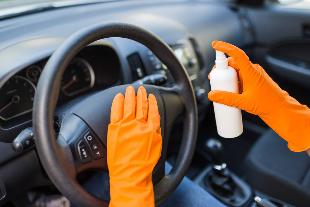 Şoför elinde araba direksiyonunu bakterilerden korumak için dezenfektan spreyi tutuyor. Antiseptik, hijyen ve sağlık konsepti. - Fotoğraf, Görsel