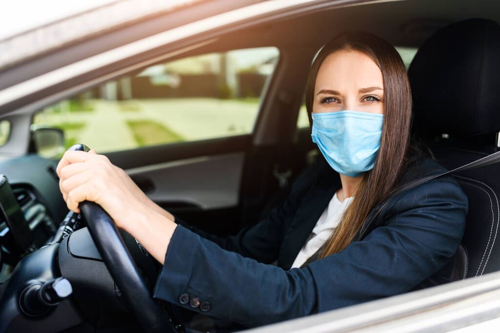 Mladá žena v ochranné masce je řízení auta - Fotografie, Obrázek