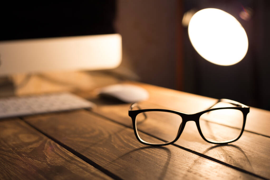 Óculos para correção de visão e visão e proteção contra computador na mesa de madeira
 - Foto, Imagem