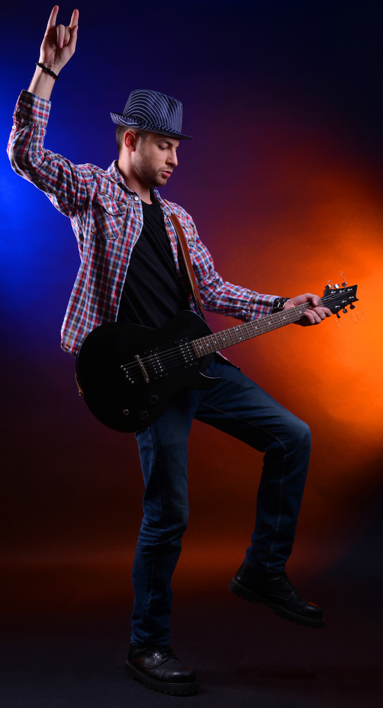 Young musician playing guitar on dark color background - Photo, Image
