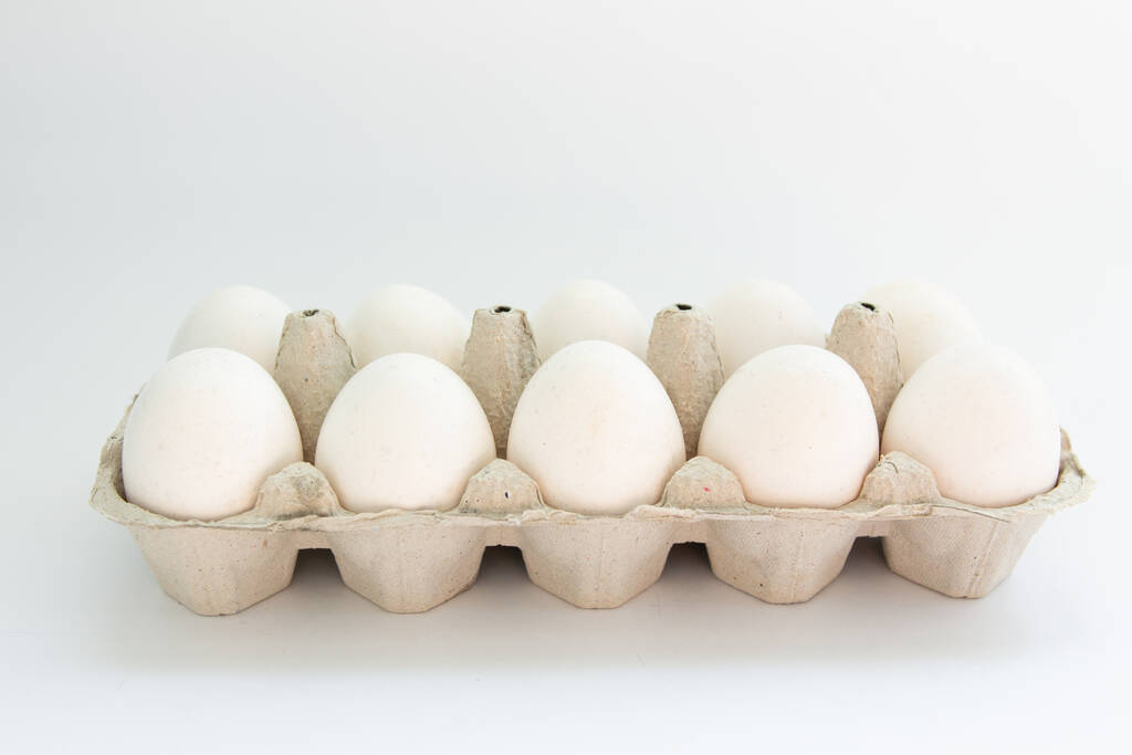 Huevos en un cartón sobre un fondo blanco
 - Foto, Imagen